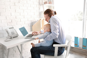 Young father with his little son working at home