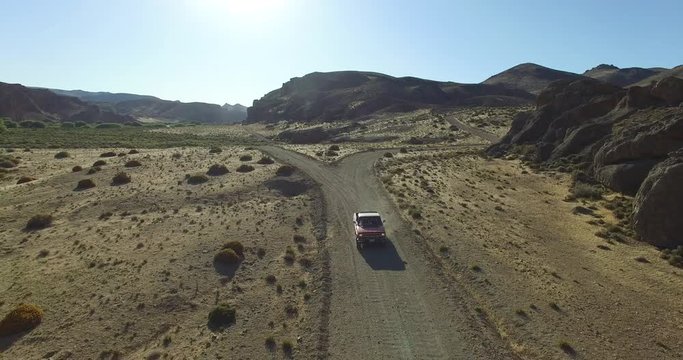Aerial scene of car traveling on dirt road a dry, rocky, landscape. Monumental scenery. Car leves dust while driving. Canyon of Piedra Parada, Chubut, Patagonia Argentina. Hiking place. 