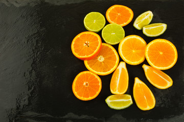 Limes, oranges and lemons on black background, copy space
