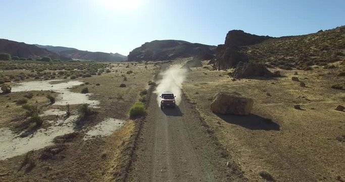 Aerial scene of car traveling on dirt road a dry, rocky, landscape. Monumental scenery. Car leves dust while driving. Canyon of Piedra Parada, Chubut, Patagonia Argentina. Hiking place. 