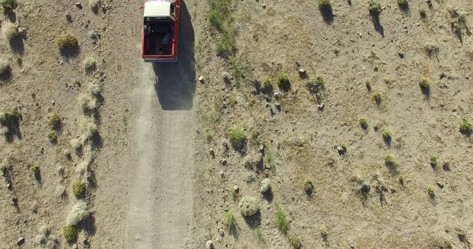 Aerial top scene of off road car in a dirt road on a desertic, dry, rocky, sand landscape. Camera follows the automobile. Piedra parada, chubut, Patagonia, Argentina.