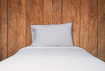 Close up white bedding and pillow on wooden texture background