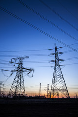 Fototapeta premium The silhouette of the evening electricity transmission pylon