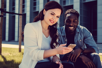 Afro american male and caucasian female with smartphone on a str