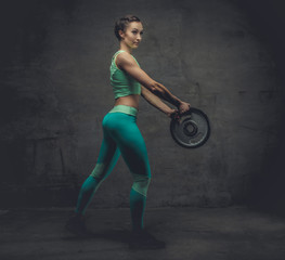 Female in azure sportswear with barbell weight.