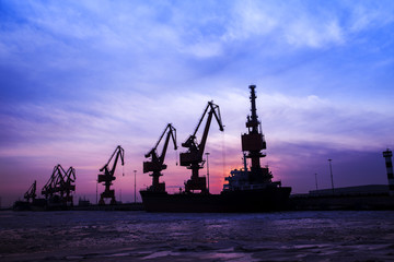 In the evening, the silhouette of port cranes