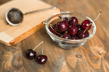 ripe cherries in glass bowl on wooden table