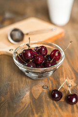 ripe cherries in glass bowl on wooden table