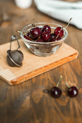 ripe cherries in glass bowl on wooden table