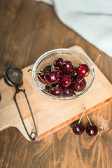 ripe cherries in glass bowl on wooden table