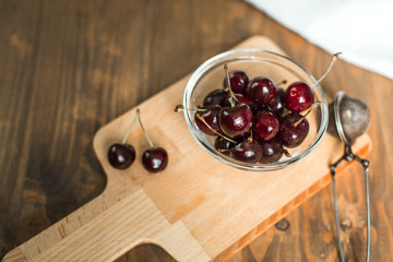 ripe cherries in glass bowl on wooden table
