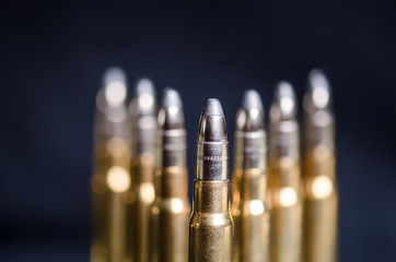 Ammunition on a dark blue background with reflection in a glass. Close up. Weapons. Bullets
