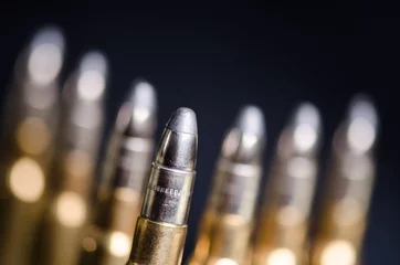 Fototapeten Ammunition on a dark blue background with reflection in a glass. Close up. Weapons. Bullets © tibor13