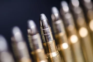 Fototapeten Ammunition on a dark blue background with reflection in a glass. Close up. Weapons. Bullets © tibor13
