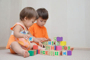 Brother and little sister constructing with toy cubes