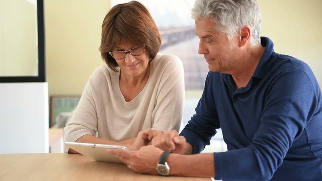 Senior couple at home using digital tablet