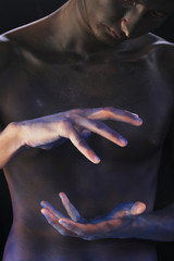 body art tinted black man's hands on the background of male body