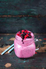 Fresh homemade yogurt smoothie wild wild berries in a glass jar on an old vintage background, closeup