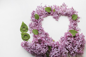 Heart from flowers of a lilac with wedding rings