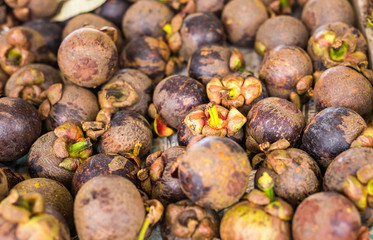 Fresh mangosteen for sale at an outdoor market.