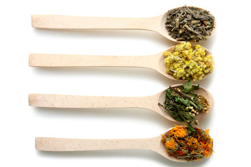 dried flowers dried herbs in wooden spoons isolated on white background