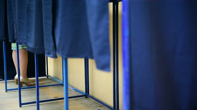 Unrecognizable people casting their votes inside voting booths during elections
