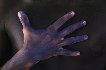 Fototapeta na wymiar body art tinted black man's hands on the background of male body