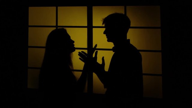 Couples fight. Angry woman hitting a man in the face. Silhouette. Close up