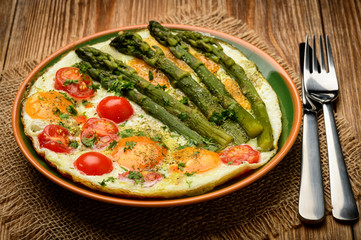 Fried eggs with green asparagus and tomatoes.