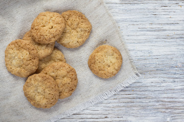 Oatmeal cookies in a linen a napkin on a light wooden background
