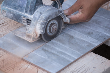 worker cutting a tile using an angle grinder