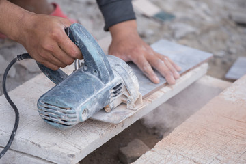 worker cutting a tile using an angle grinder