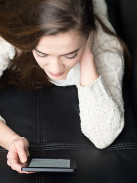 Girl reading e book on the sofa at home.