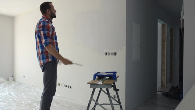 Unhappy man painting wall at his new home
