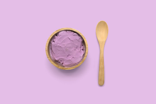 Homemade taro ice cream in wooden bowl with spoon on purple background