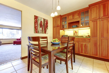 Bright orange wood kitchen and dining room with tile floor.