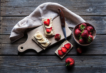 Fruity toast on wooden background. Strawberries, bread, butter a