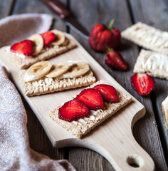 Fruity toast on wooden background. Strawberries, bread, butter and cheese.Vintage style