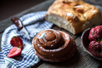 delicious breakfast with strawberries and sweet bun on wooden ba