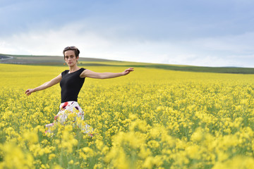 Young woman cheering in canola field in the summer