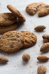 Cookies pile with chocolate chip and almond on light textile background. Delicious morning snacks for breakfast, brunch and lunch. Appetizing, healthy and fast food