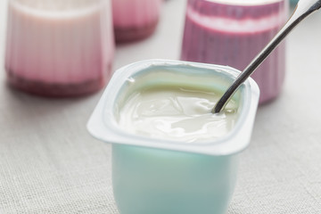 Yogurts assortment  in plastic bowls on light cloth background. Natural and fruit healthy, diet, gourmet dessert for granola breakfast. Sweet yoghurts closeup.