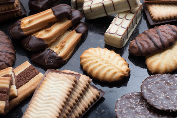 Cookies assorted on black background. Delicious morning snacks for breakfast, brunch and lunch. Appetizing, sweet and fast food.