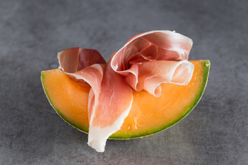 Jambon mix. Ham. Traditional Italian and Spanish salting, smoking, dry-cured dish - jamon Serrano and prosciutto crudo sliced with melon on grey background. Copy space. Closeup. - 112718777