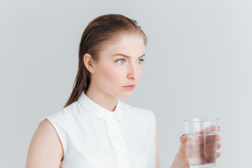 Thoughtful woman holding glass with water