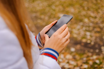 The girl holds a mobile phone in hand outdoor