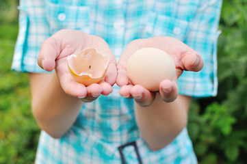 The girl holds the broken egg in hand