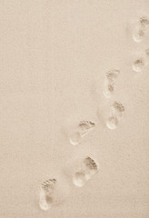 Line of footprints in smooth white desert sand