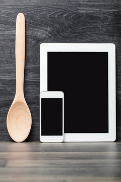Smartphone and tablet wood spoon on wooden table. Concept online food, Eating technology.