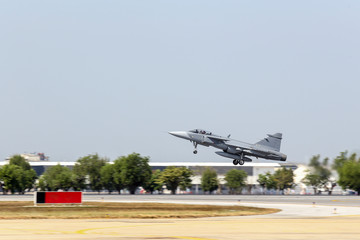 jet fighter aircraft with landing gear take off from runway with max power
